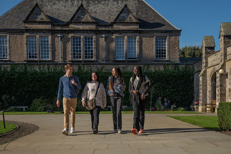 A group of students walking towards the camera in St Salvators quad on a sunny day.